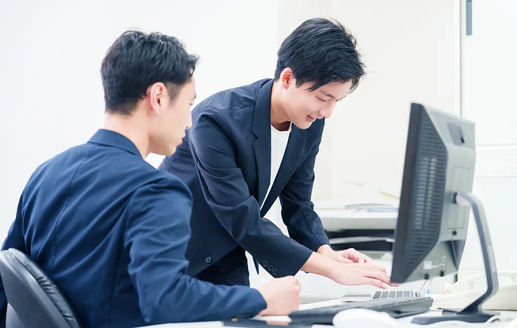 PCの前で笑顔を見せるITエンジニア