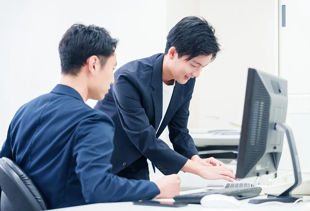 PCの前で笑顔を見せるITエンジニア
